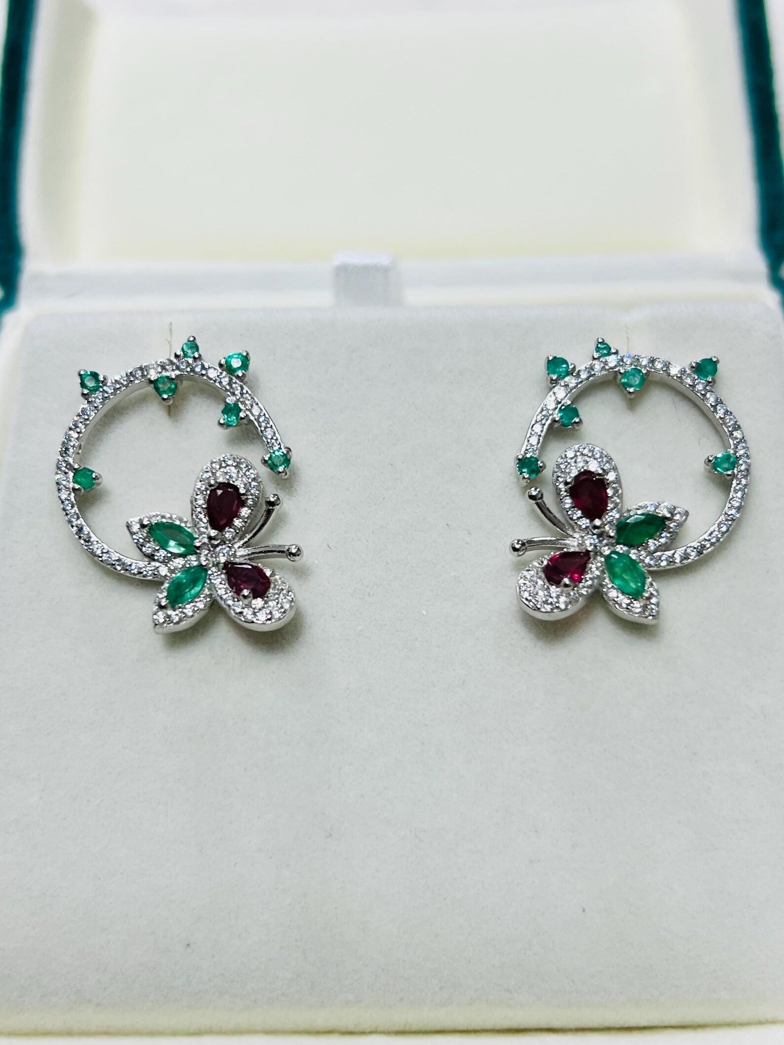Exquisite gemstone butterfly and flower earrings with sparkling clear and green stones, in a white setting.