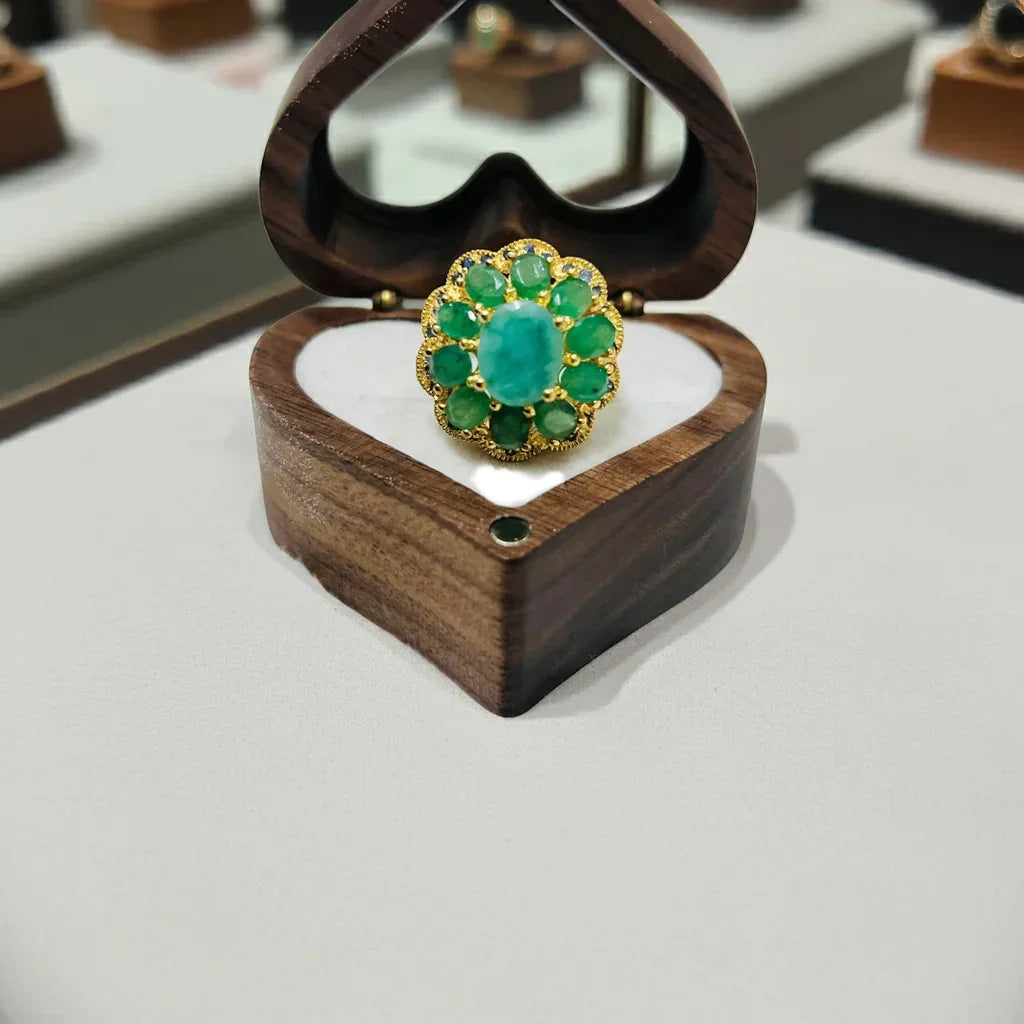 Green gemstone ring in a wooden box on a white surface