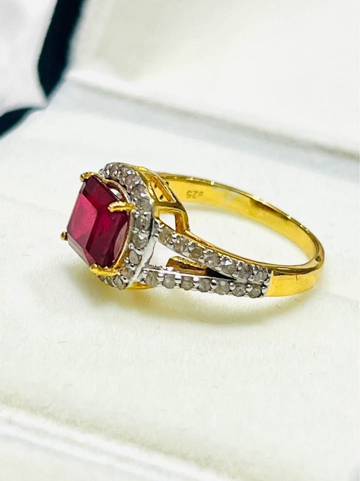 Angled view of genuine ruby and natural diamond gold ring in open jewelry box, 925 stamped