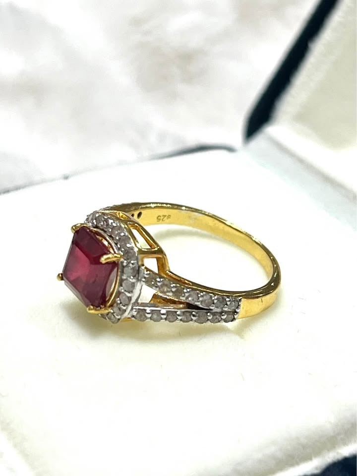 Genuine ruby and natural diamond gold ring with visible 925 stamp, resting partially in box.