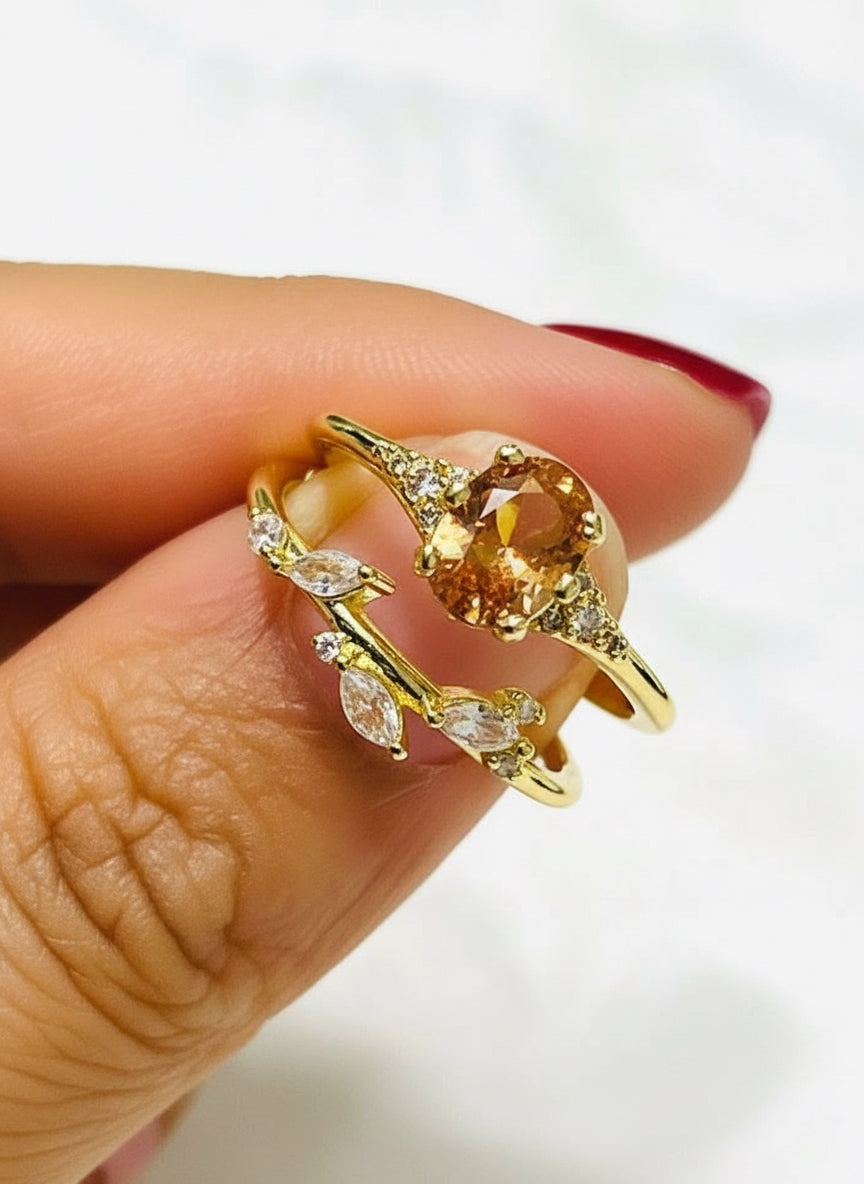 Close-up of a gold-tone duo ring set with an oval orange gem and a leaf-inspired band.