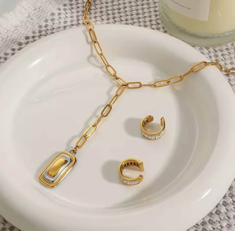 18K gold filled paperclip lariat necklace with matching clear crystal ear cuffs on a white plate.