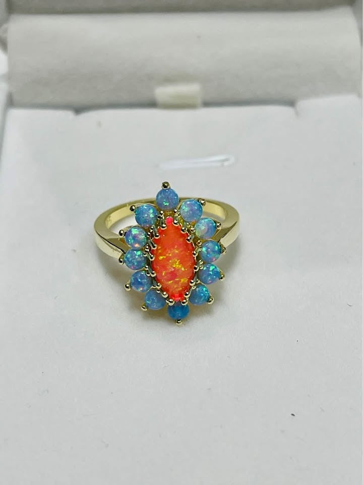 Eye-catching sterling silver ring featuring a central orange opal and halo of blue opals.