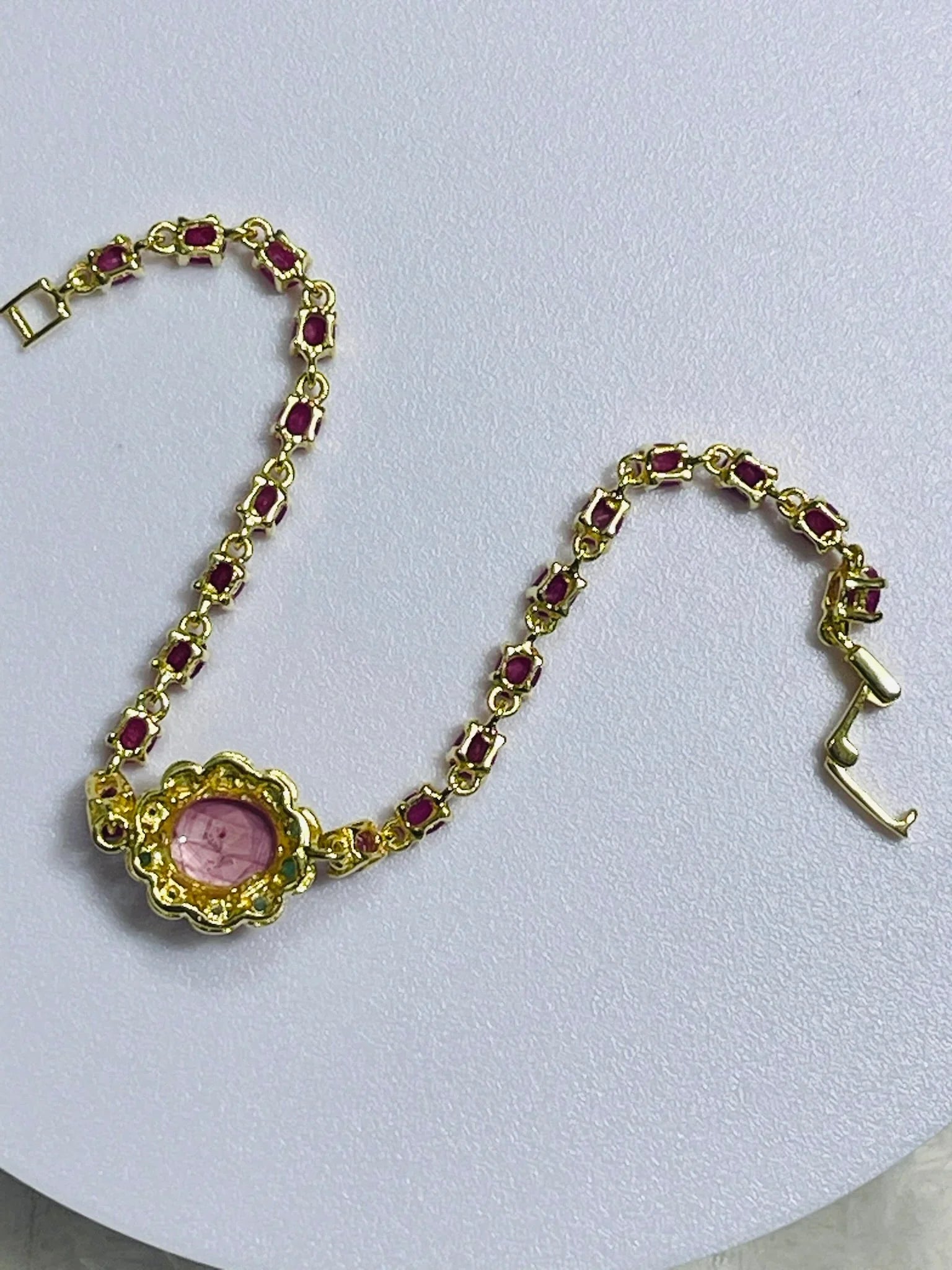 Reverse view of a gold bracelet, revealing the intricate back settings of the oval ruby gemstones and central cabochon.