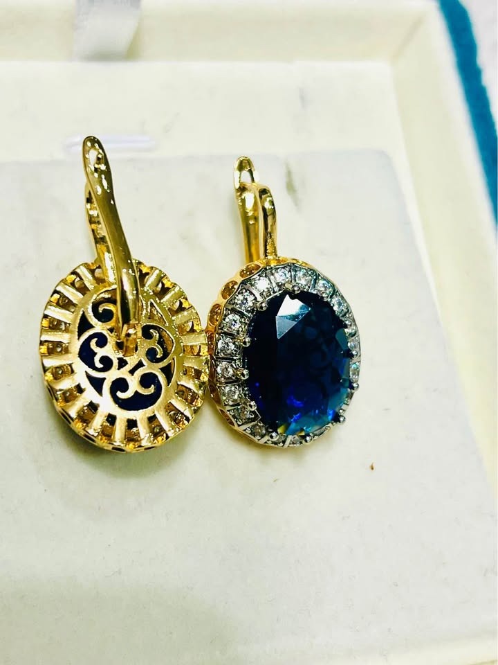 Close-up of sapphire and diamond halo earrings, showcasing intricate gold filigree on the back.