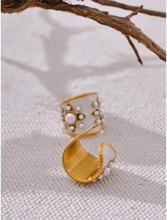 One vintage gold vermeil white enamel hoop earring with pearls and a branch accent on a white fabric.