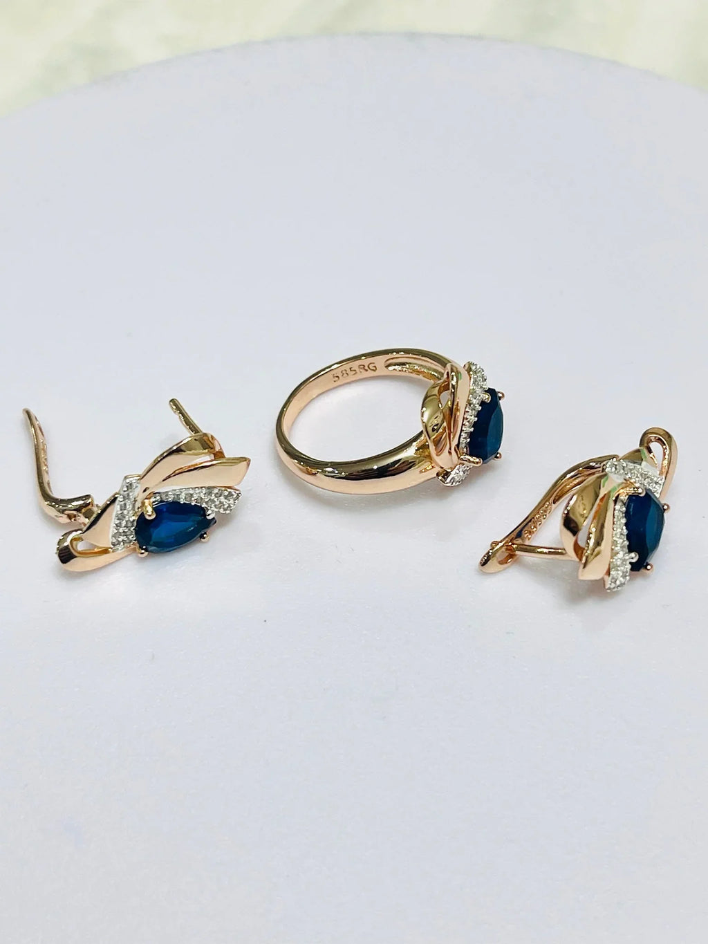 Gold jewelry set with blue gemstones on a light gray background