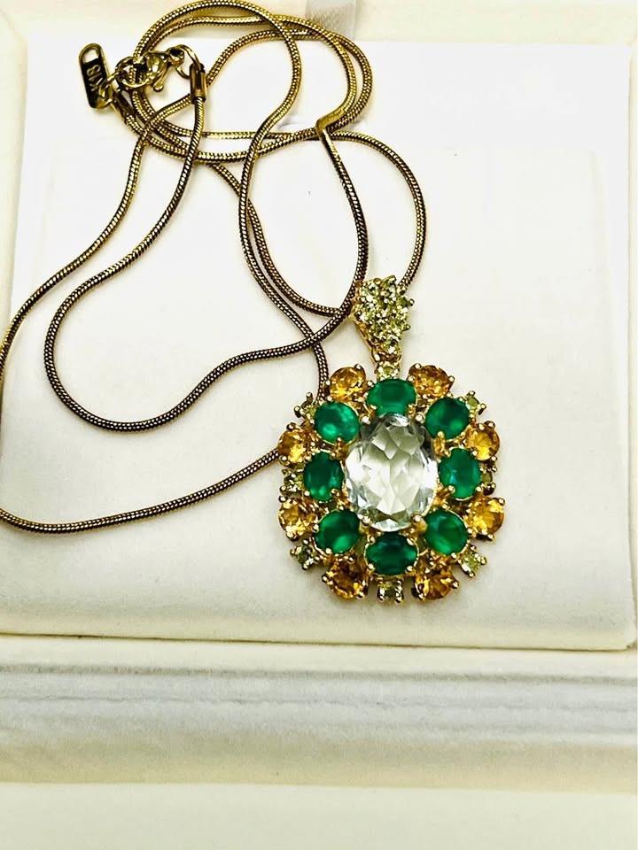 Detailed view of a vibrant green amethyst, green agate, and sapphire pendant necklace on a gold chain.