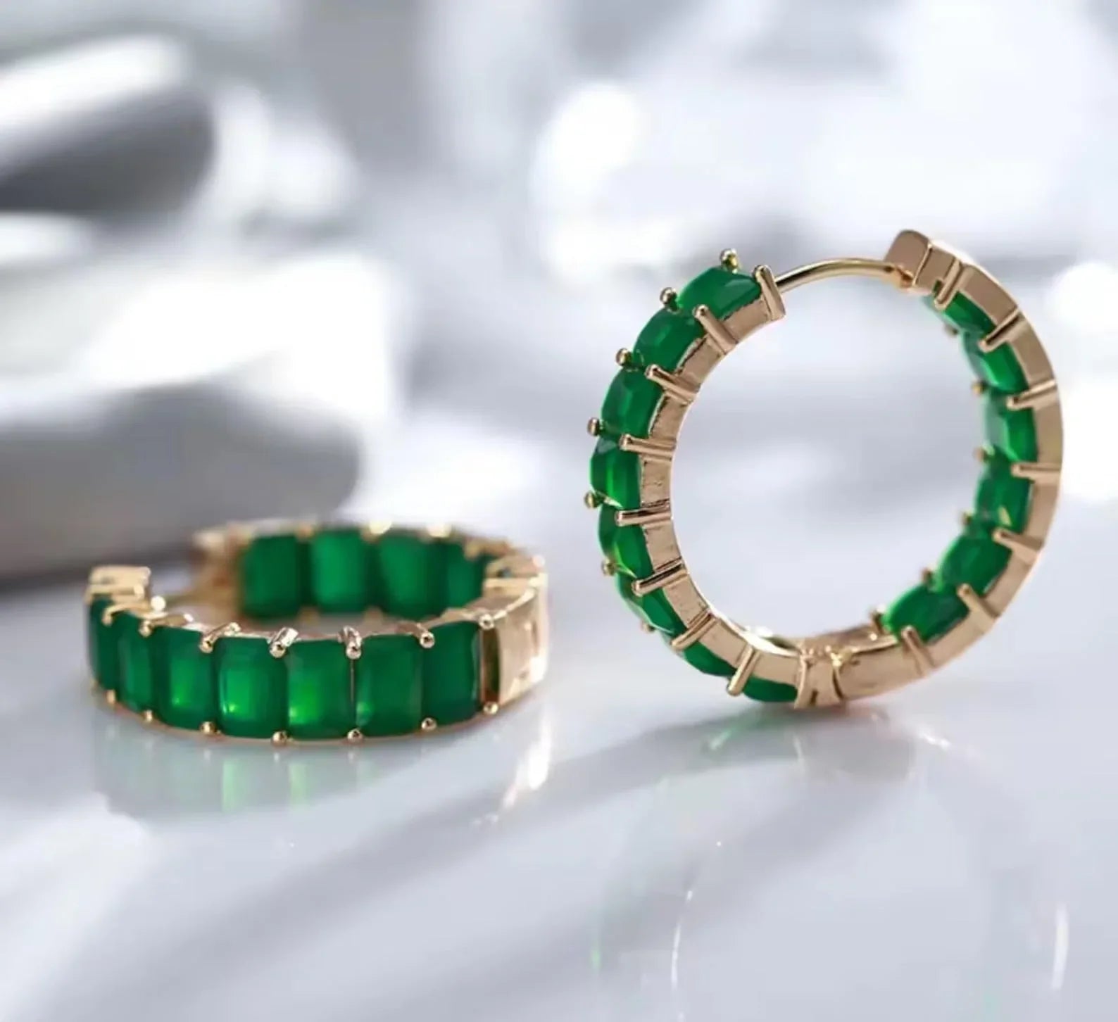  Stunning pair of green matrix emerald hoop earrings with gold-tone setting on a light background.