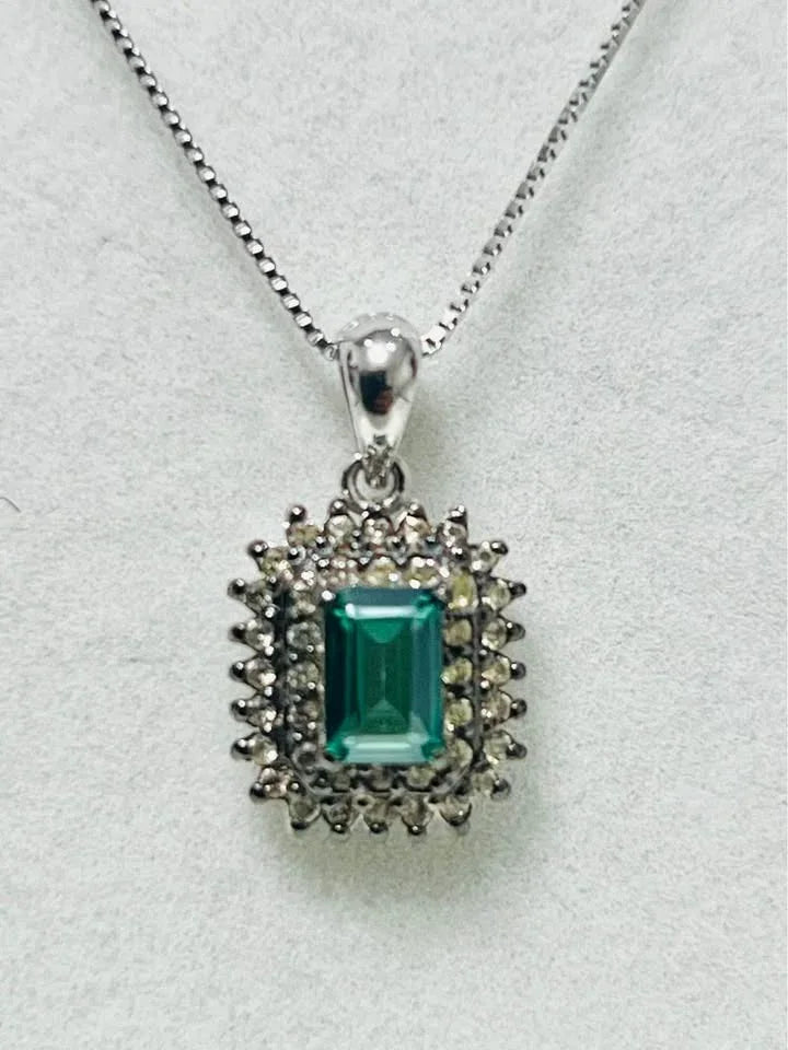 A close-up view of a stunning green tourmaline pendant surrounded by dazzling diamonds on a silver chain