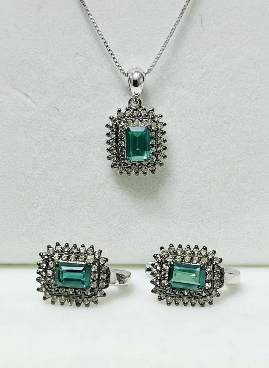 Beautiful green tourmaline and diamond jewelry set, including a pendant and two rings, elegantly displayed.