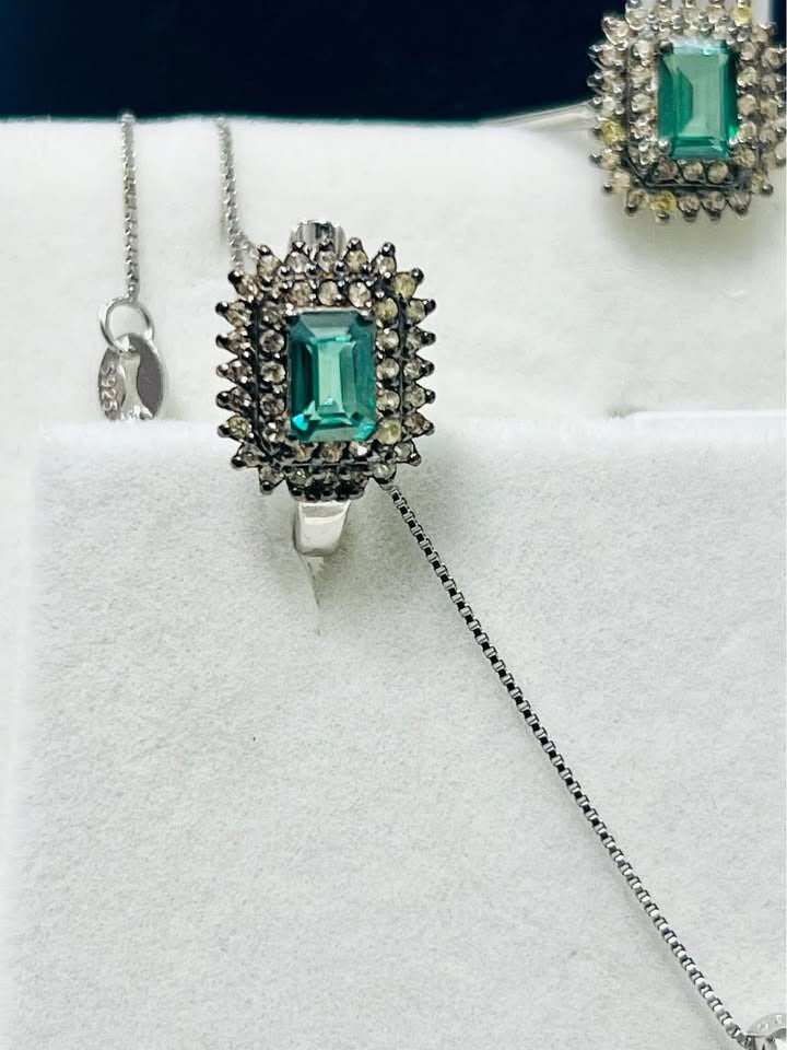 Detailed close-up of a green tourmaline ring surrounded by diamonds, part of a matching jewelry set