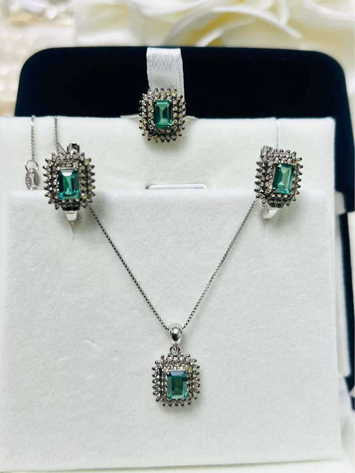 Full green tourmaline and diamond set with ring, matching earrings, and a sparkling pendant on display