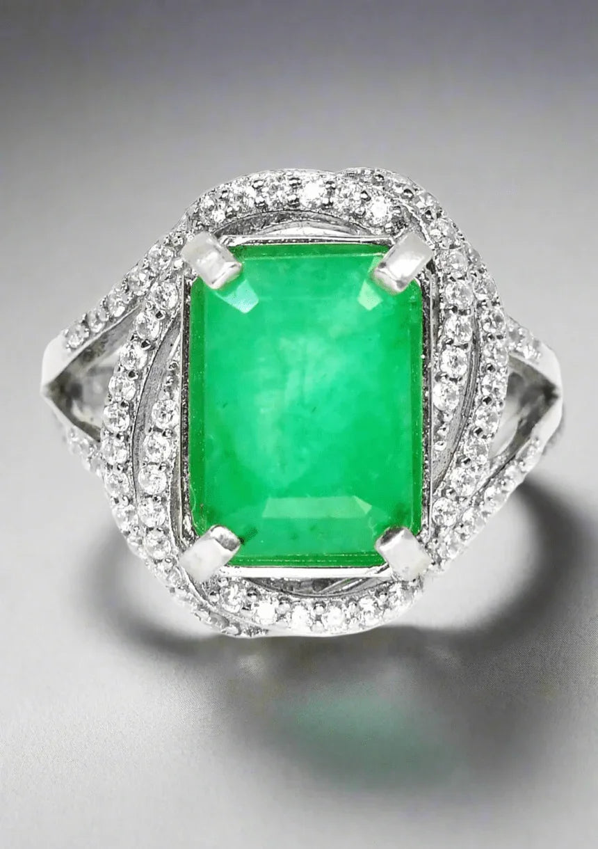 Top view of a handcrafted emerald ring with brilliant CZ accents, featuring rhodium-plated sterling silver.