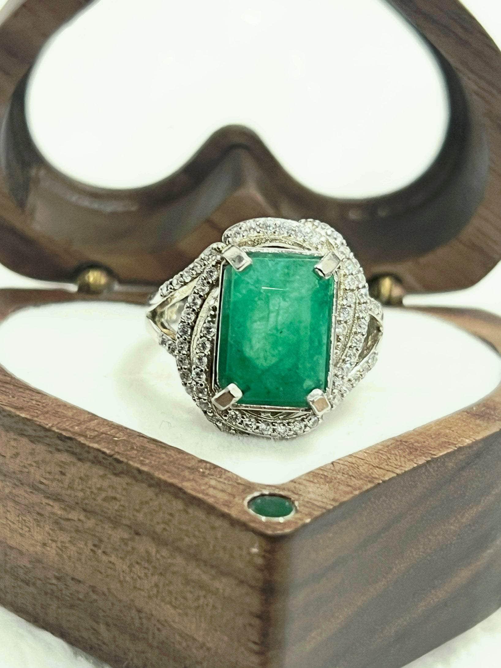 Handcrafted emerald ring with CZ accents, beautifully displayed in an open heart-shaped wooden gift box.