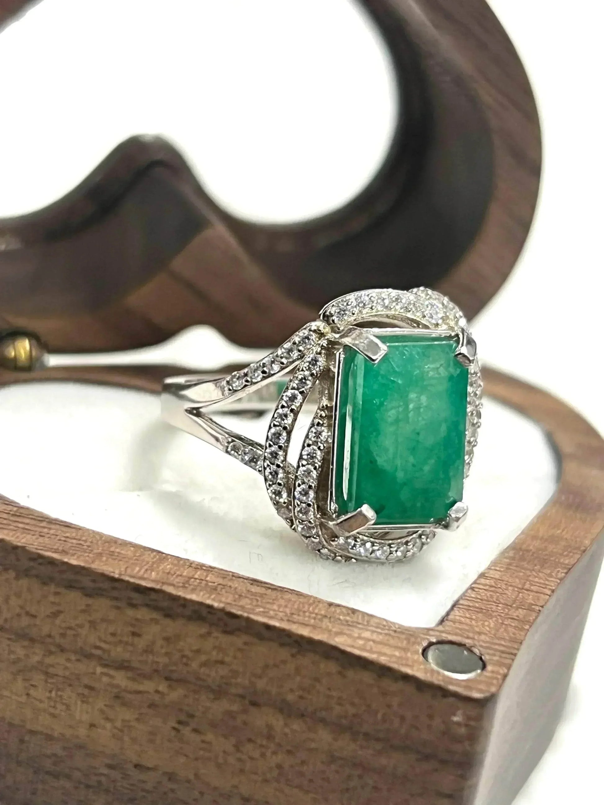 Close-up of a handcrafted emerald ring with CZ accents, highlighting its intricate design within a gift box.