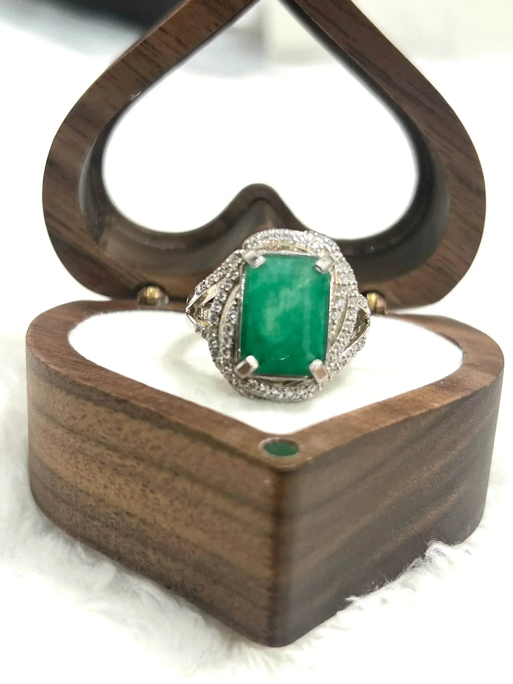 Luxurious handcrafted emerald ring with CZ accents, stunningly showcased in a heart-shaped wooden box.
