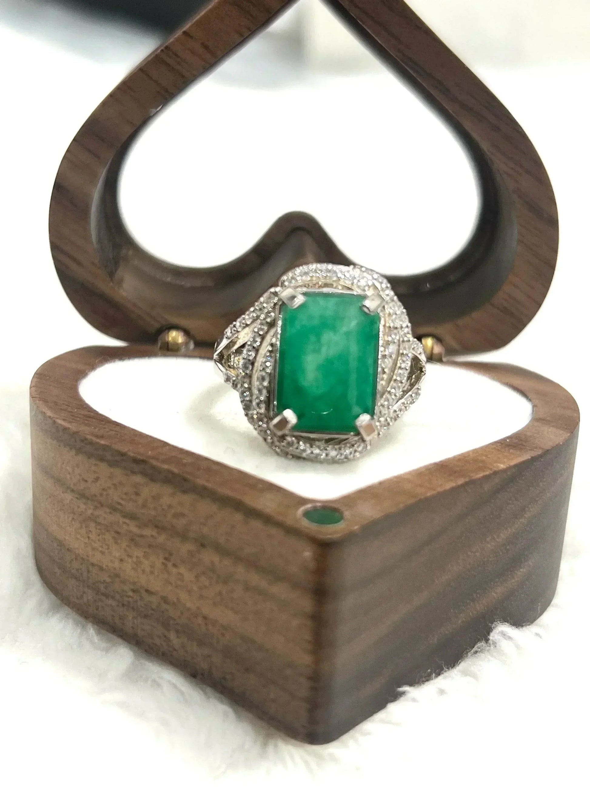 Luxurious handcrafted emerald ring with CZ accents, stunningly showcased in a heart-shaped wooden box.
