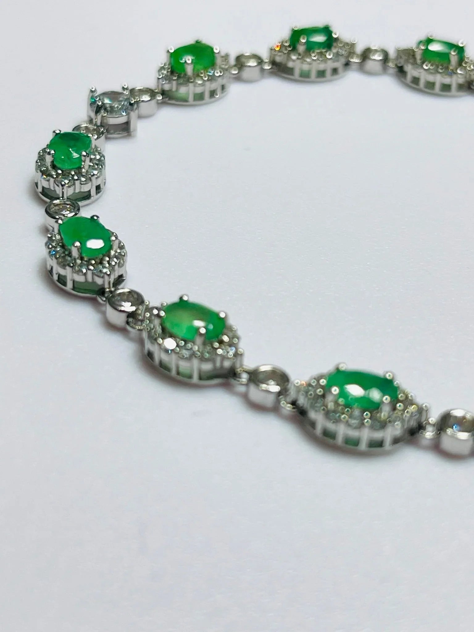 Angled view of a luxurious handcrafted sterling silver bracelet, highlighting its 6x4mm oval Colombian emeralds.