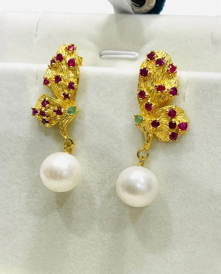 Pair of handmade sterling silver butterfly earrings with rubies, emeralds, and dangling pearls.