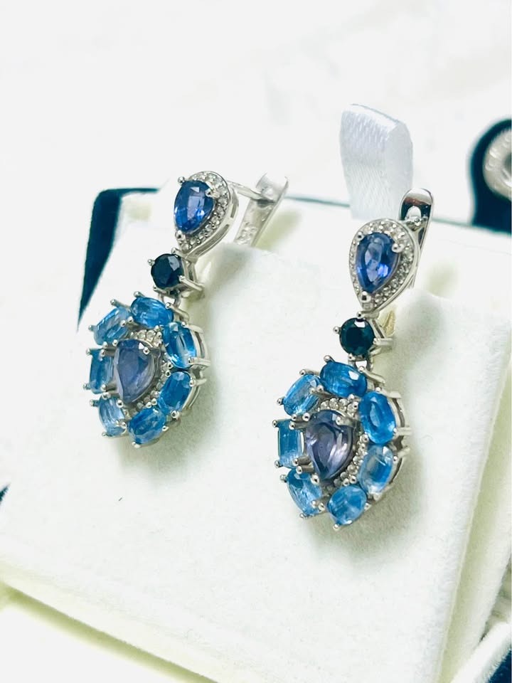 Angled view of handmade sapphire and iolite dangle earrings, showcasing their craftsmanship on a white display.