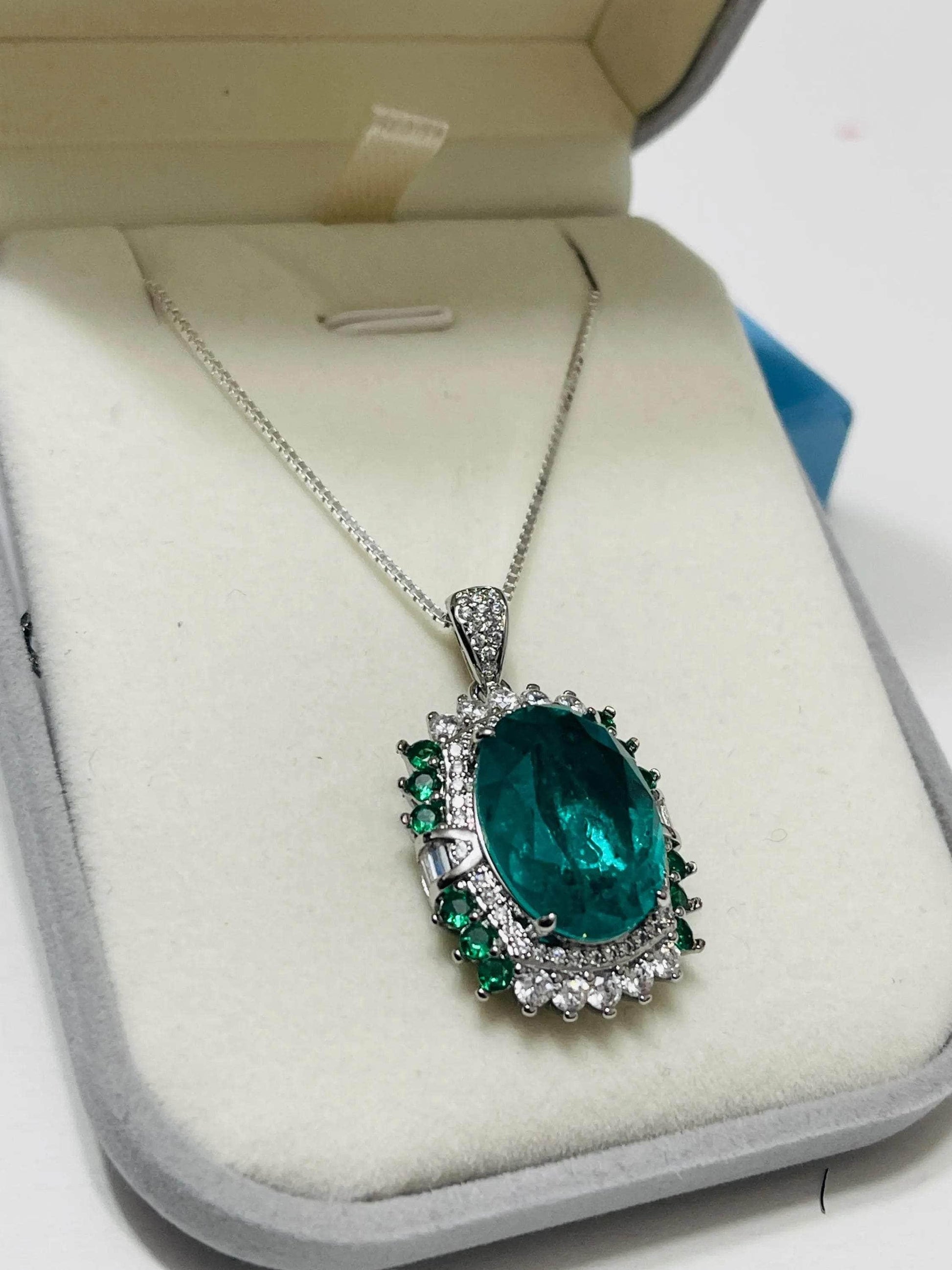 Oval lab-created emerald pendant necklace with white and green accents on an Italian sterling silver chain in a gray box.