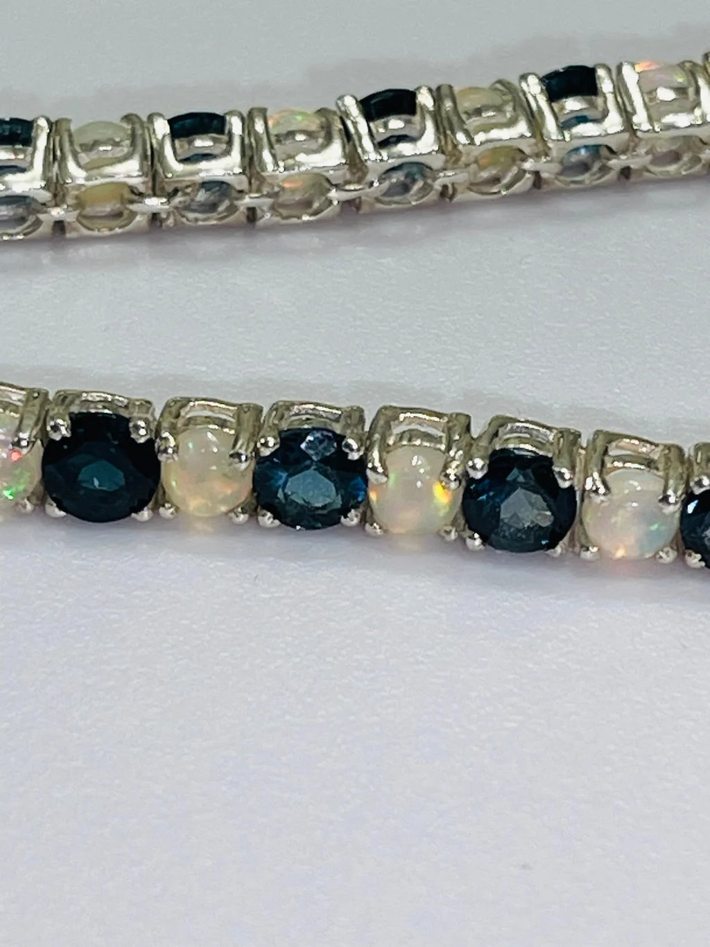 Close-up of a London Blue Topaz and Opal tennis bracelet, showcasing alternating gemstones in sterling silver.