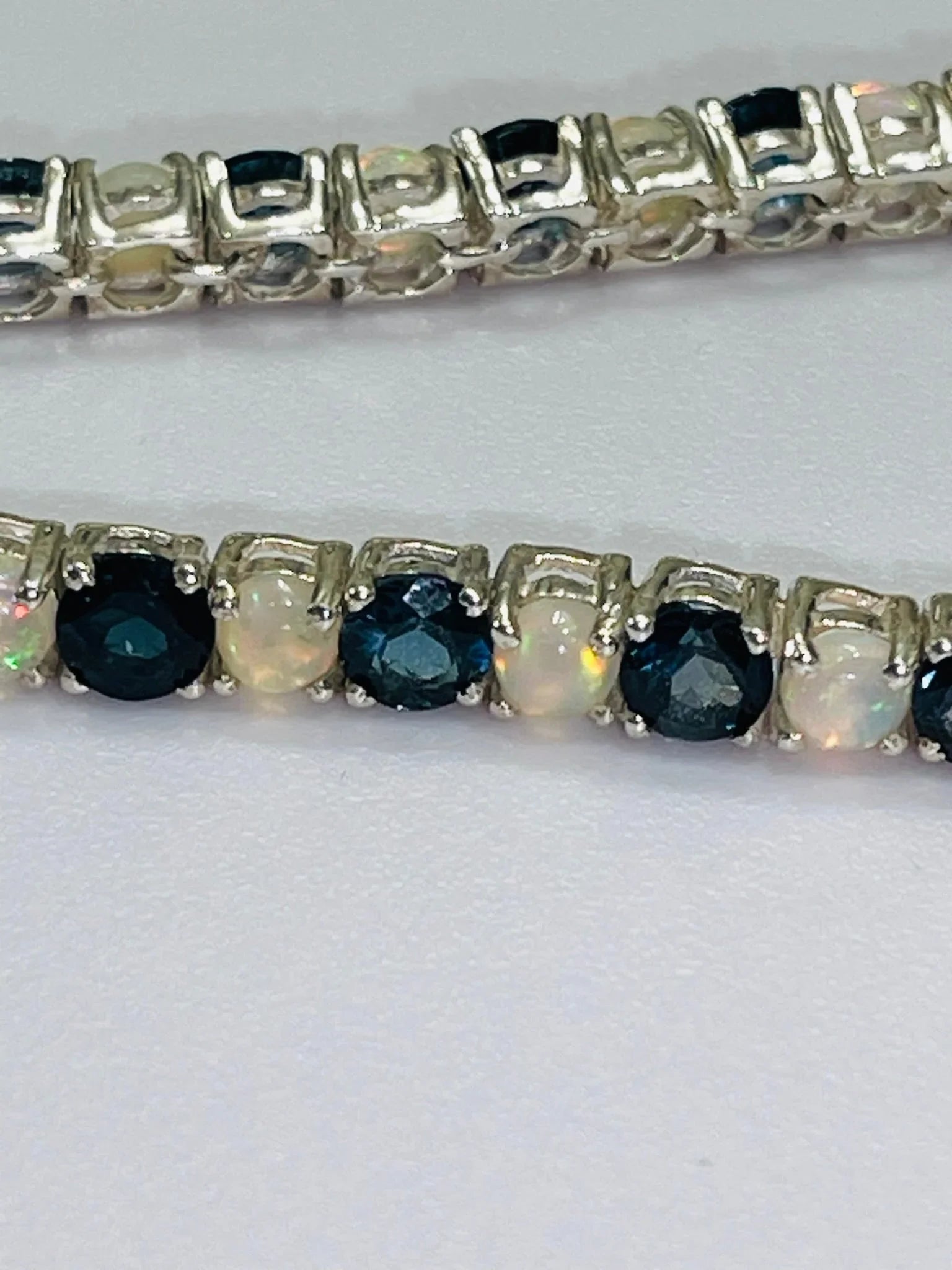 Close-up of a London Blue Topaz and Opal tennis bracelet, showcasing alternating gemstones in sterling silver.