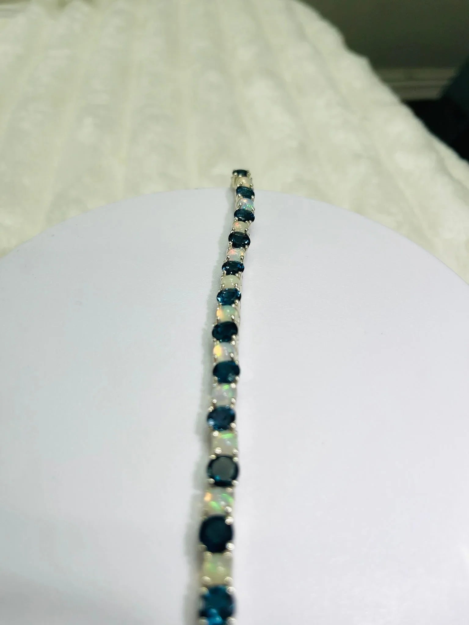 London Blue Topaz and Opal tennis bracelet displayed on a white surface, elegant and sparkling.