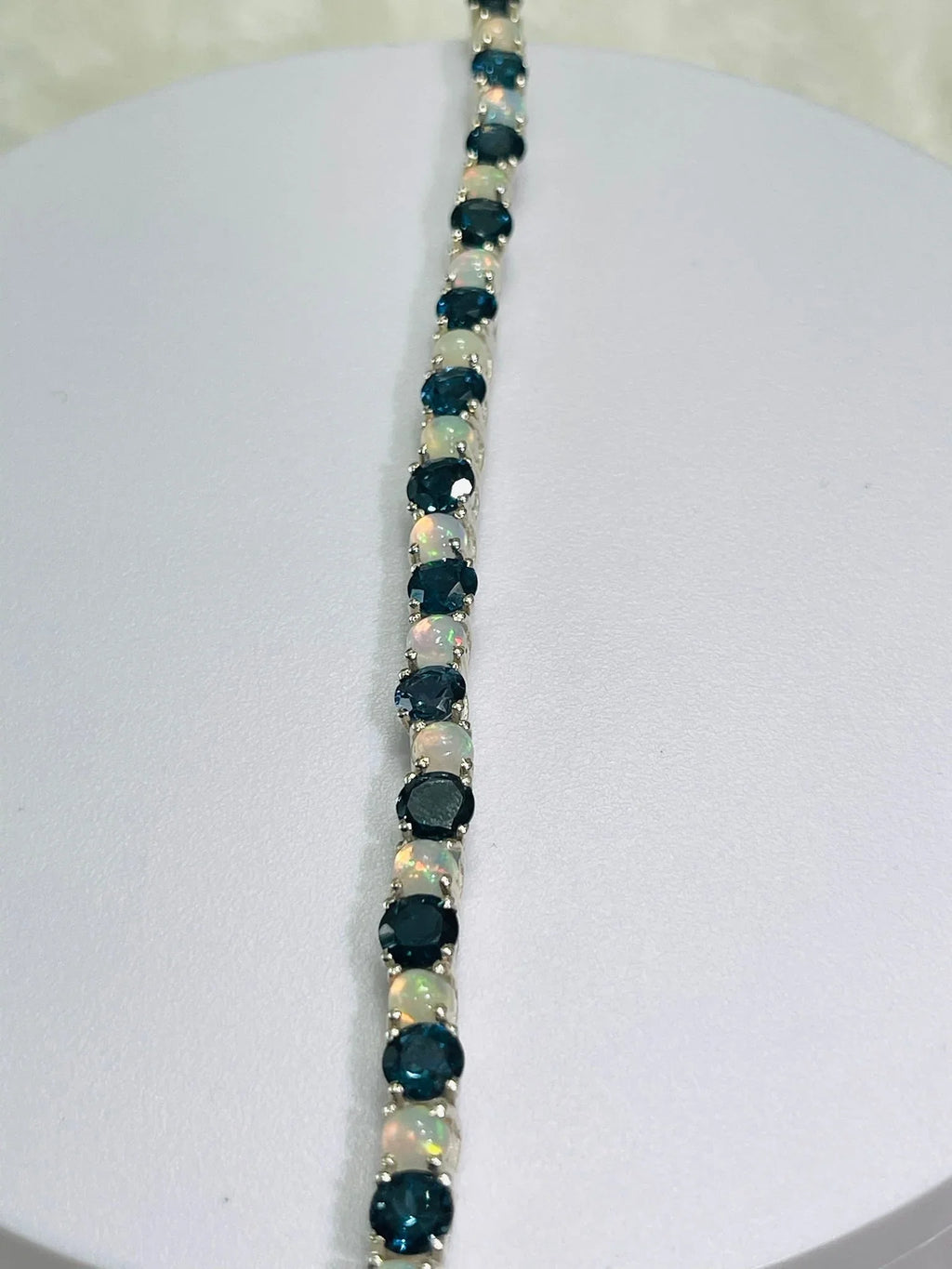 Full length view of a London Blue Topaz and Opal tennis bracelet, highlighting its continuous gem line.