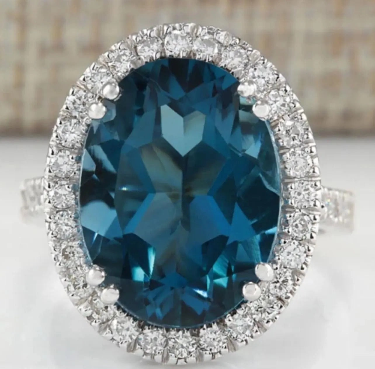 Close-up of an oval London Blue Topaz halo ring with brilliant white accent stones, highlighting gemstone clarity.