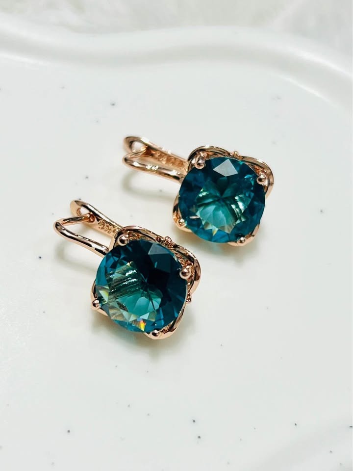 Angle view of 14K rose gold earrings featuring vibrant London Blue Topaz gemstones.