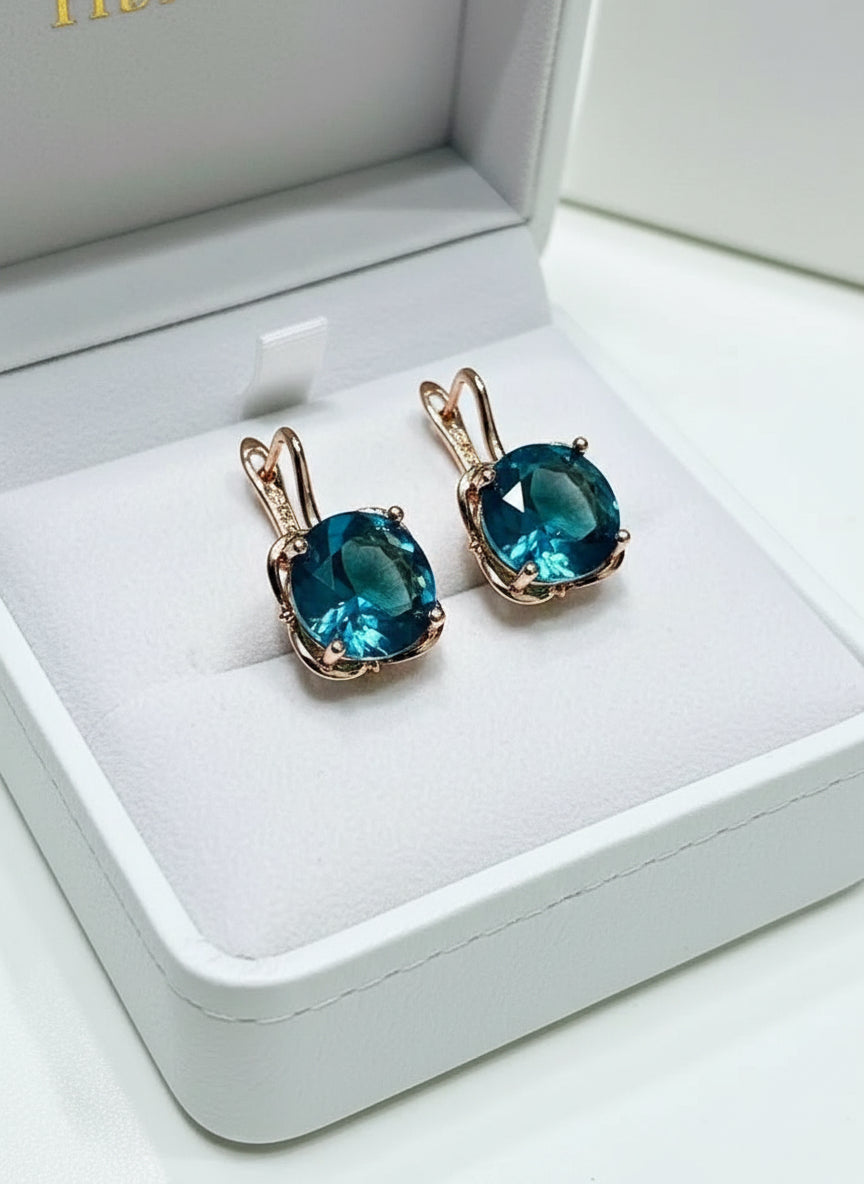 Symmetrical view of a pair of 14K rose gold London Blue Topaz earrings, stunning blue.