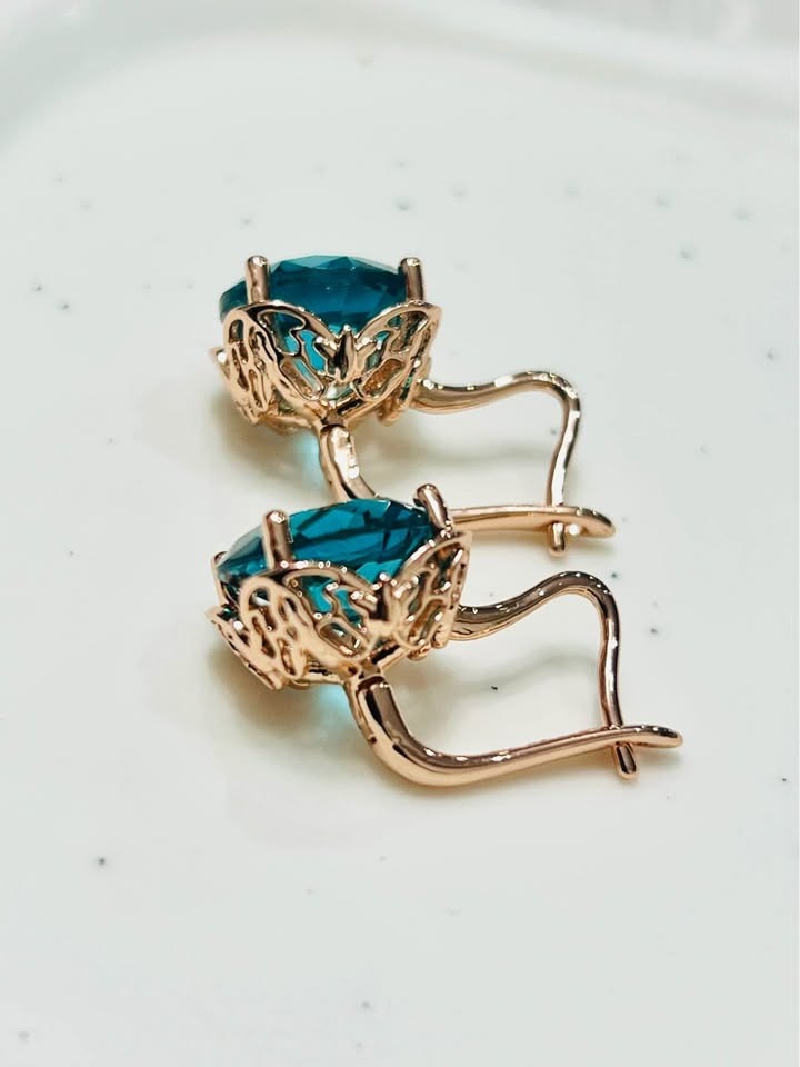 Side view of 14K rose gold London Blue Topaz earrings, highlighting intricate metalwork.