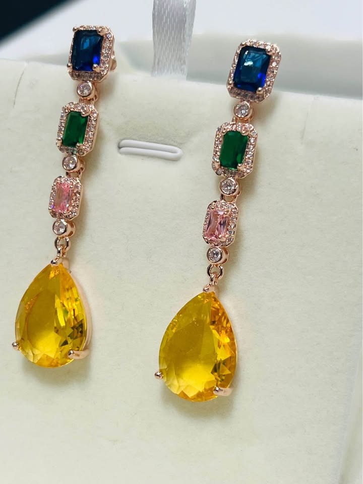 A close-up shot of the long dangle earrings, showcasing the various colored gemstones and setting.