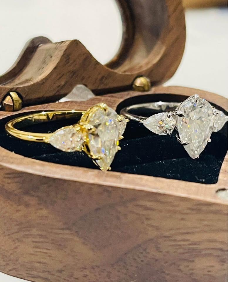 Luxurious 4 carat moissanite rings in gold and silver settings, displayed side-by-side in a chic wooden box.