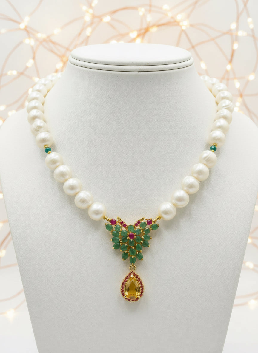 Luxurious South Sea pearl necklace adorned with natural Colombian emeralds, rubies, and a citrine drop, displayed beautifully.