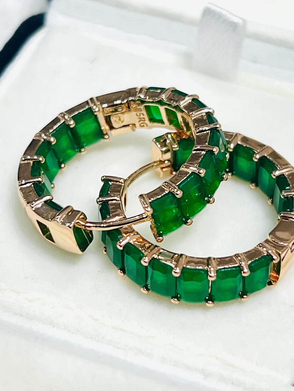  Pair of rich green matrix emerald hoop earrings with rose gold plating, clasps open in box.