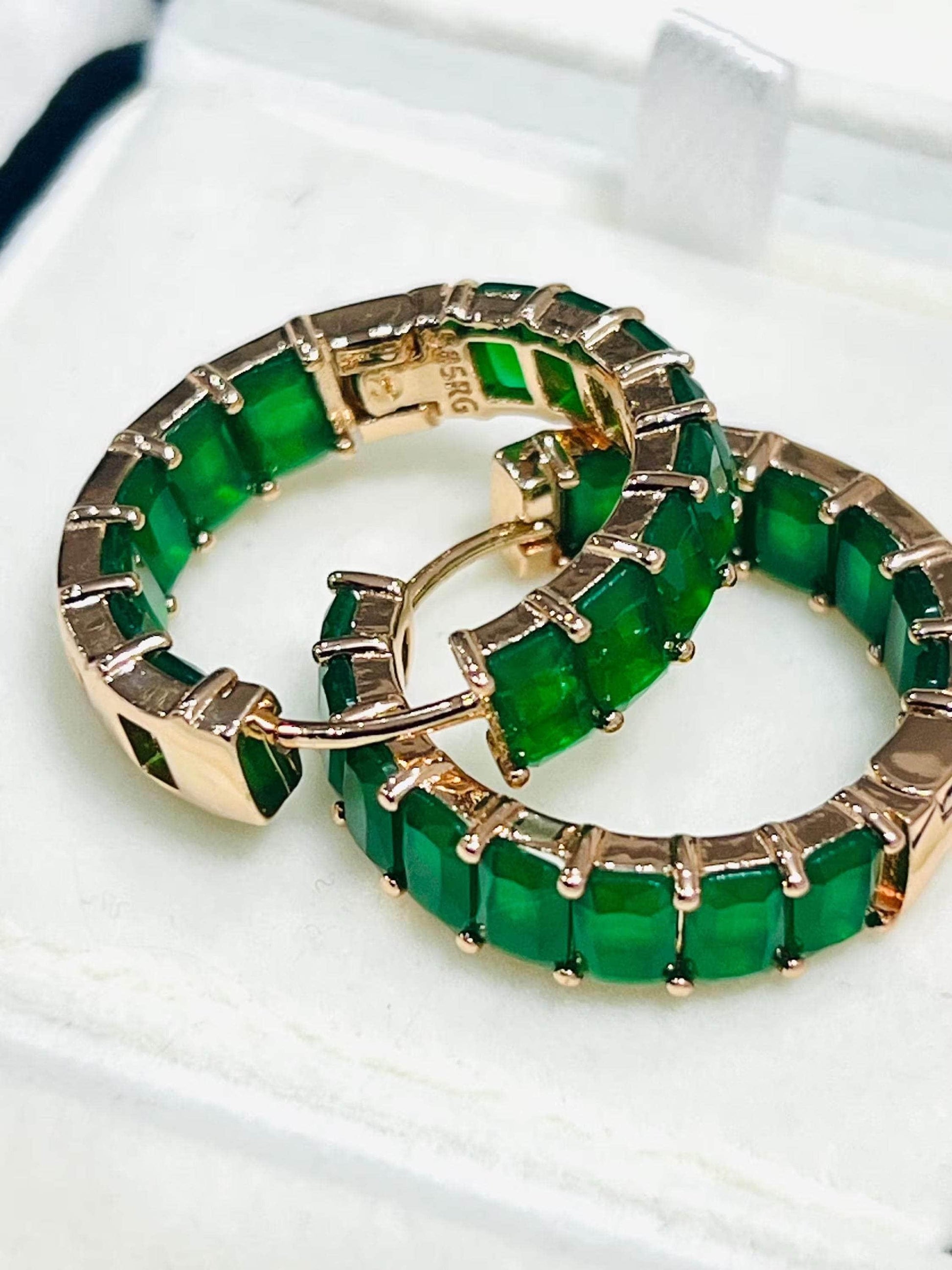 Pair of rich green matrix emerald hoop earrings with rose gold plating, clasps open in box.