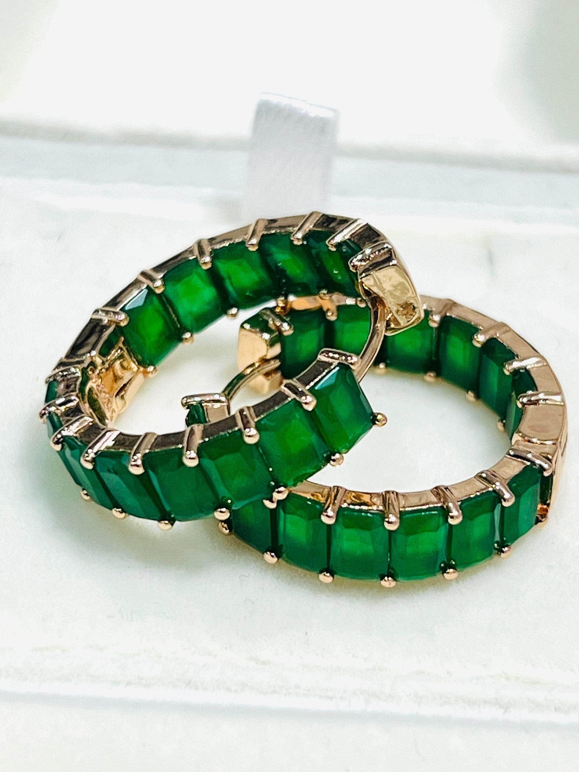 Two vibrant green matrix emerald hoop earrings with rose gold plating, stacked in a white jewelry box.