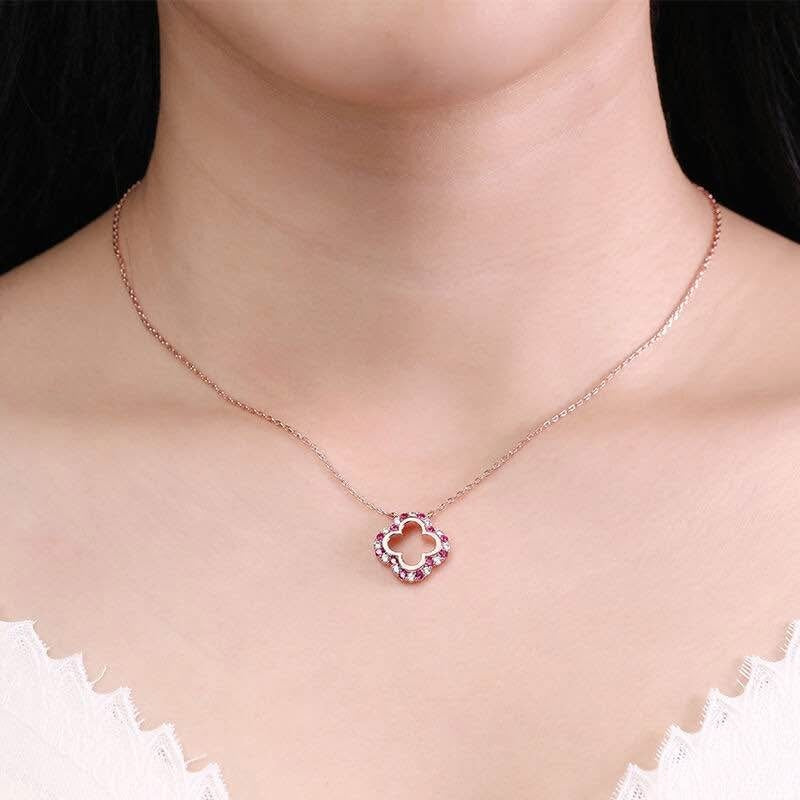  Woman wearing a delicate rose gold clover necklace with ruby and moissanite, perfect for everyday elegance.