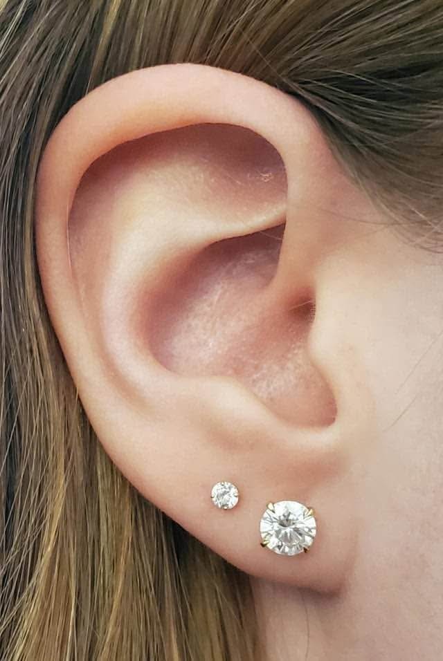  A woman wearing a 14k gold Moissanite stud earring, demonstrating its size and elegant appearance on the ear.
