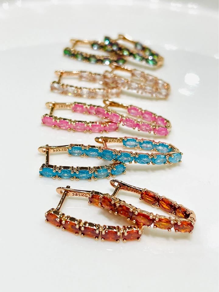  A stack of multi-colored V-shaped inside-out tourmaline hoop earrings, showing a range of vibrant colors.