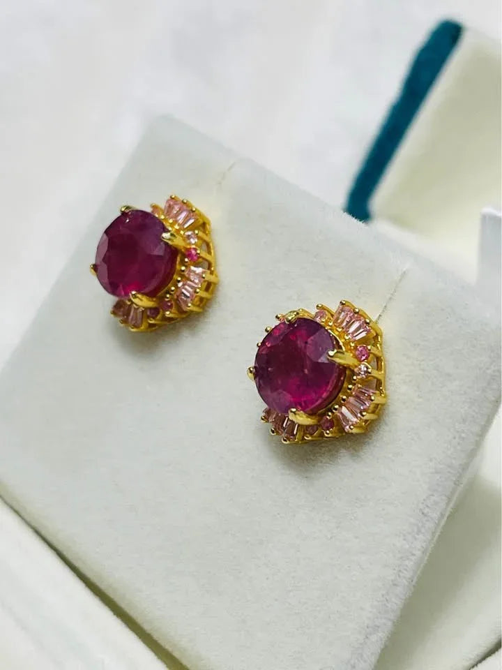 A close-up of a floral cluster ring. The design features a center tanzanite, surrounded by emeralds 