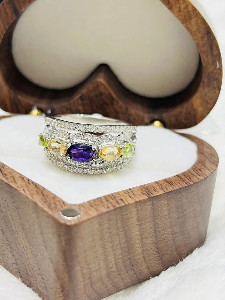 Exquisite multi-gemstone ring featuring natural amethyst, peridot, and citrine, displayed in a heart-shaped wooden box.