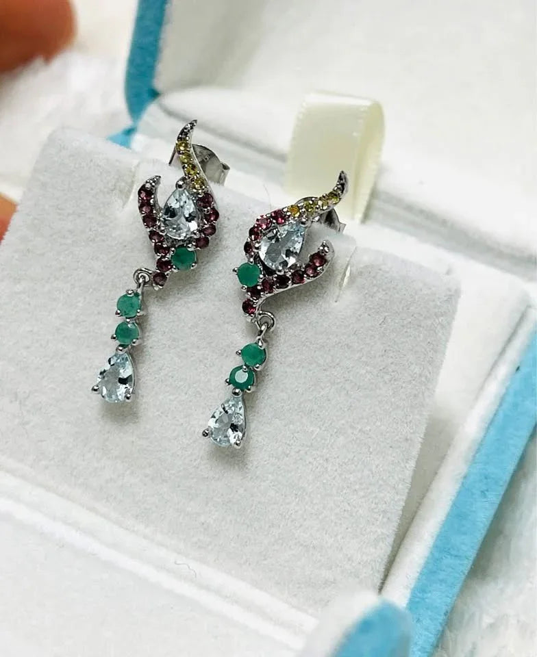 Elegant sterling silver drop earrings with natural aquamarine, emerald, and garnet, displayed in a box.