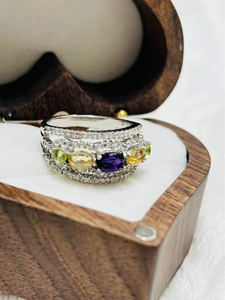 Side view of a unique natural amethyst, peridot, and citrine band ring with sparkling accents in a box.
