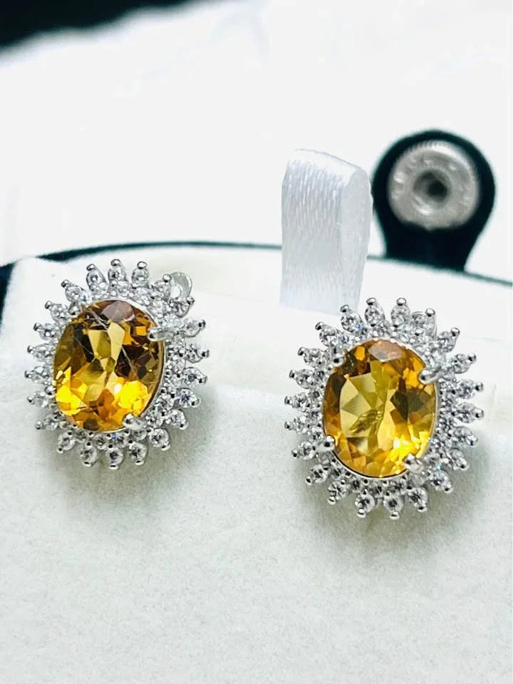  Top-down angled shot of natural citrine oval halo earrings, vibrant yellow stones.