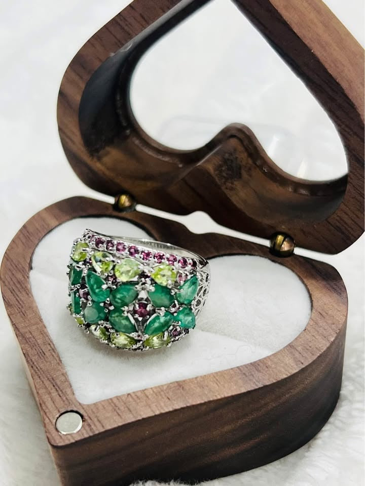 Angled view of a 4.6 carat ring with a gorgeous arrangement of vibrant natural emerald, peridot, and rhodolite garnet.