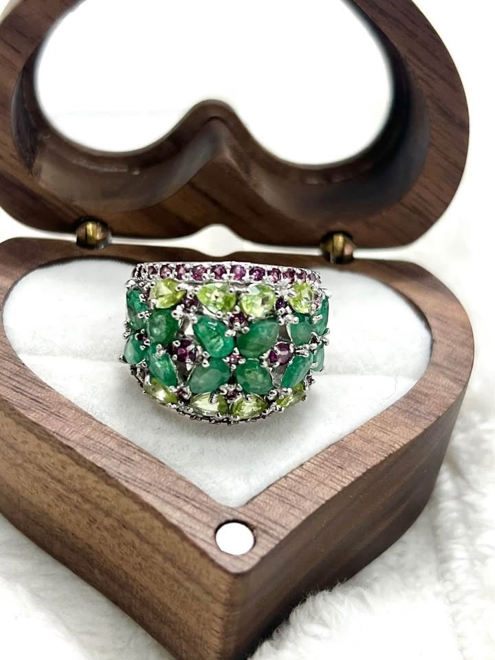 Side detail of the 4.6 carat natural emerald, peridot, and rhodolite garnet ring, showing the intricate setting.